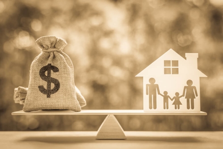 Money bag and house with family one balancing scale